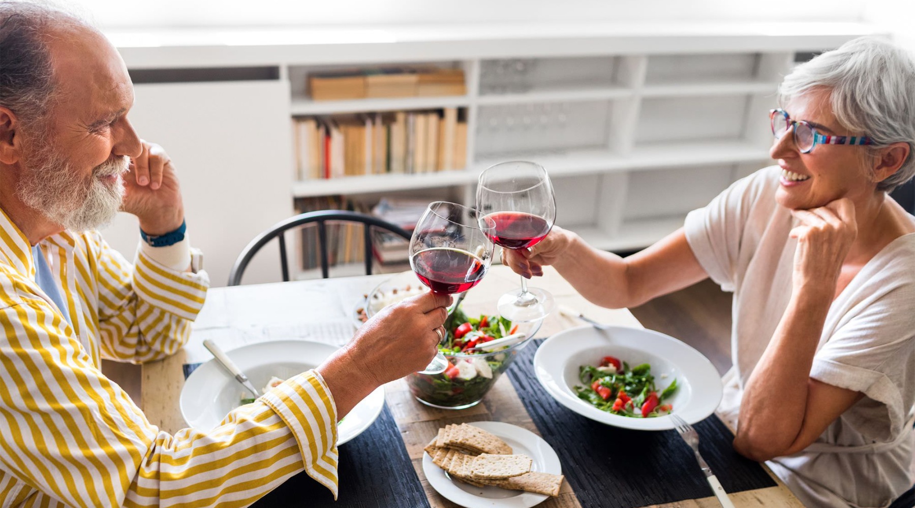 a couple sits at a table eating with wine