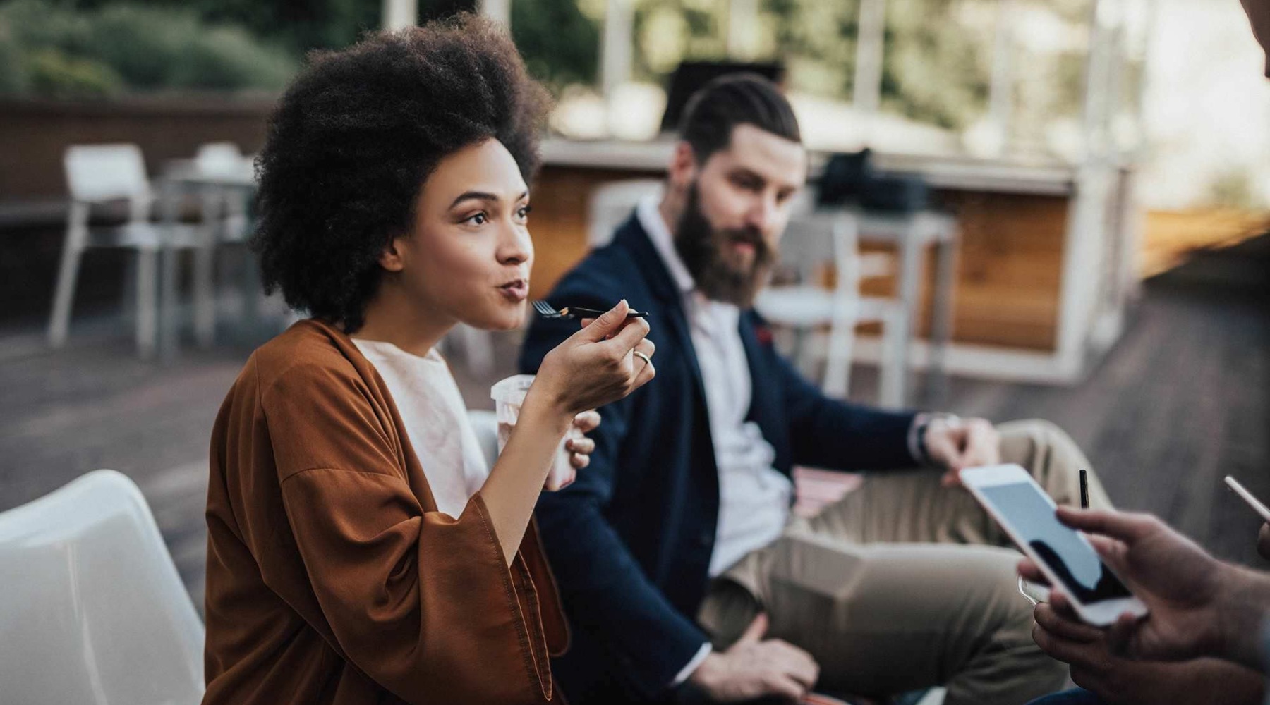 people sitting at a table with food and a phone